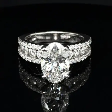 Oval diamond engagement ring with rows of round diamonds across a wide white gold band
