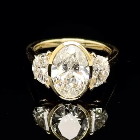 Bezel-set oval diamond with half-moon side diamonds on a yellow gold band
