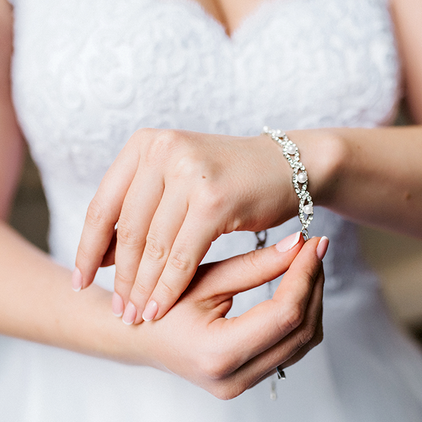 Bride in a white lace dress wearing a diamond bracelet