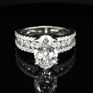 Oval diamond engagement ring with rows of round diamonds across a wide white gold band