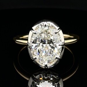 Large oval diamond solitaire with white gold prongs on a yellow gold band