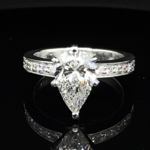 Pear-shaped diamond engagement ring with diamonds set along a white gold band